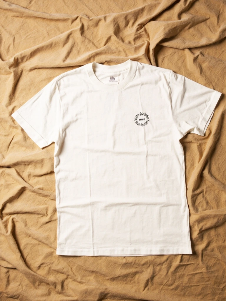 Off-white tee with botanical-wreath illustration on a warm sweep