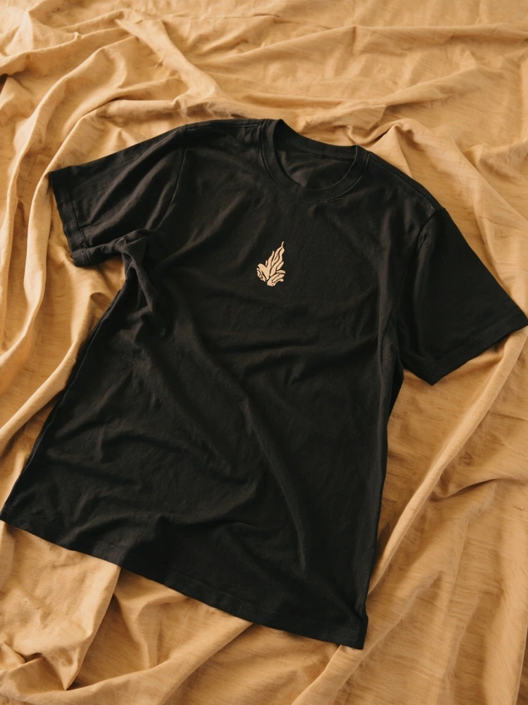 Charcoal tee with hands-and-flame illustration on a warm sweep