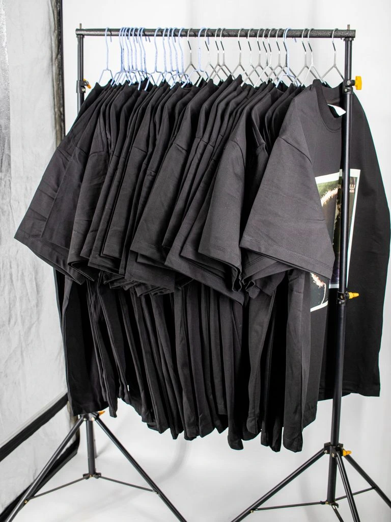 Black tee with single-word cream serif print on a warm sweep