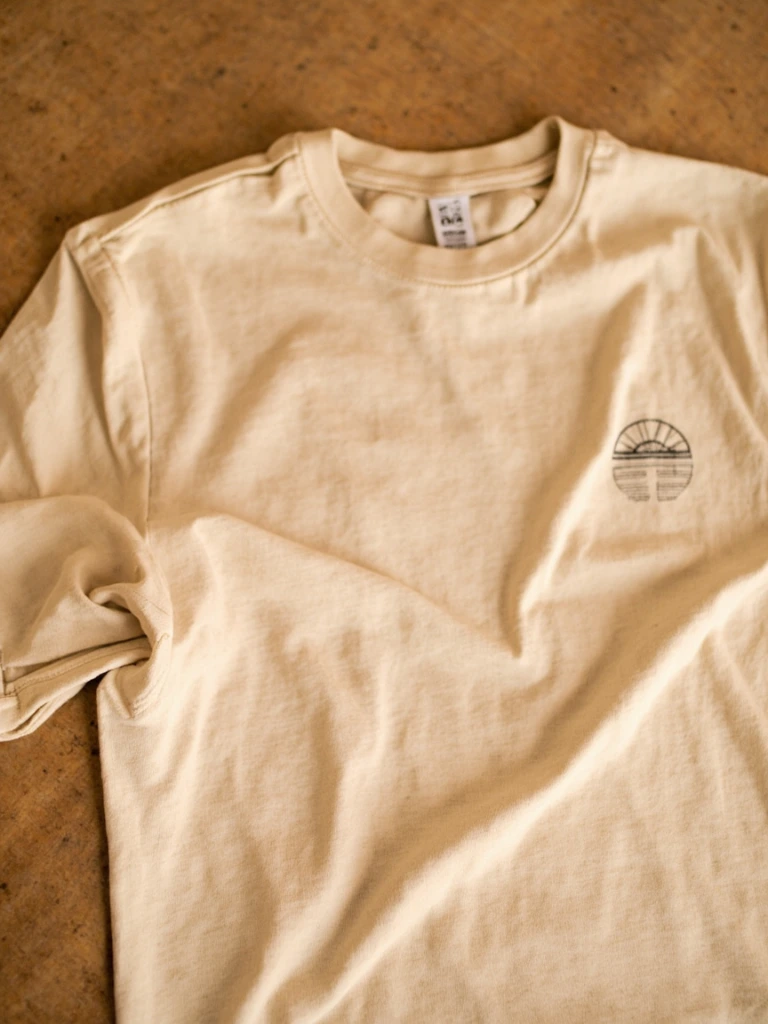 Oatmeal tee with rising-sun illustration on a warm sweep